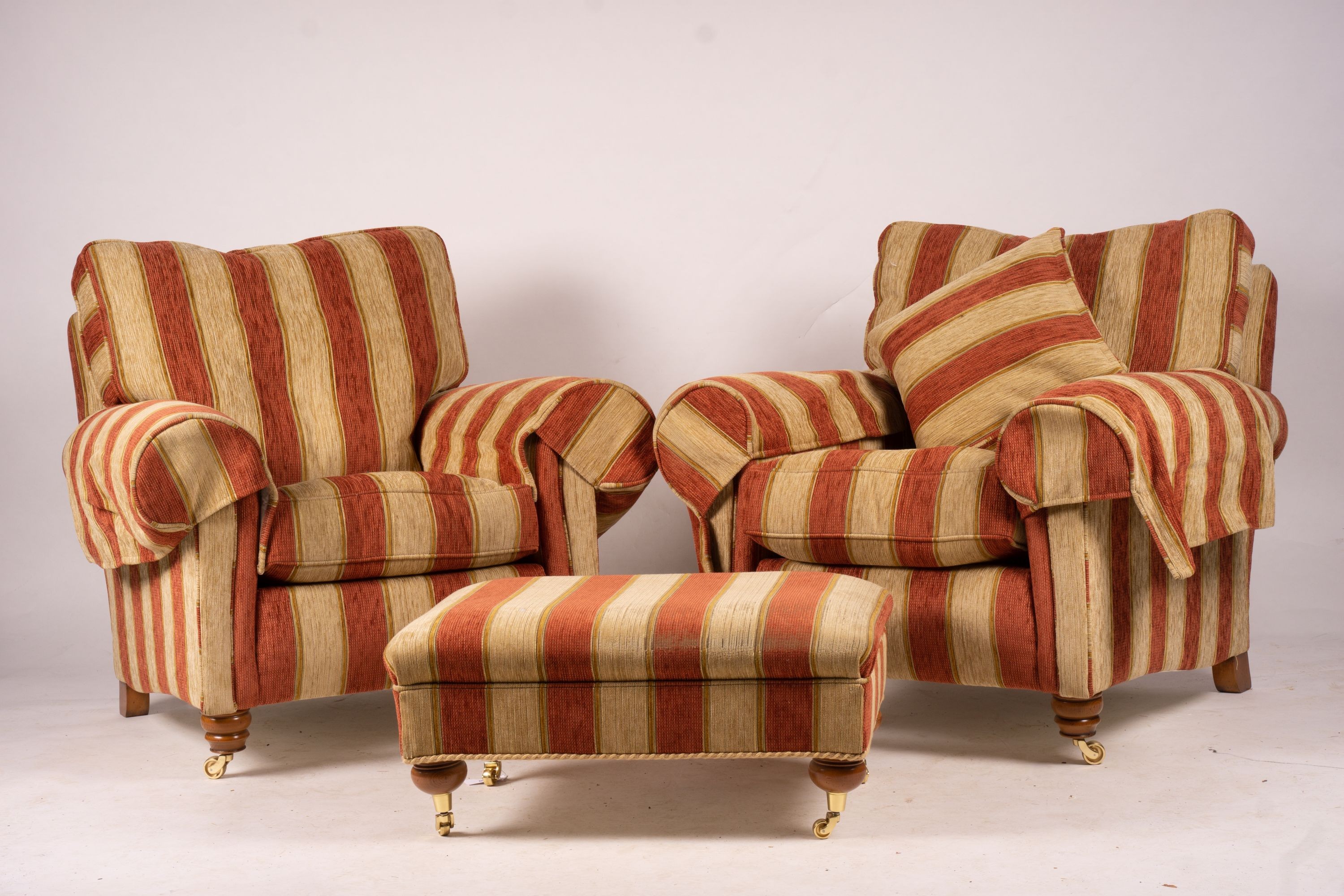 A pair of Duresta armchairs, width 94cm, depth 90cm, height 90cm and matching footstool in striped red and gold fabric